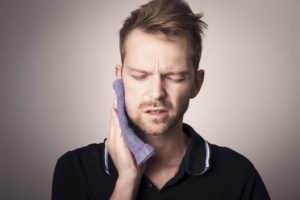 Man in pain holding his cheek with hand, suffering from bad tooth ache