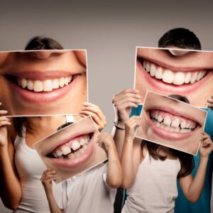 young family with children holding a picture of a mouth smiling on a gray background