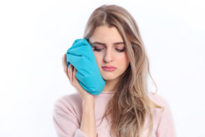 A woman holding an ice pack to her jaw after a root canal