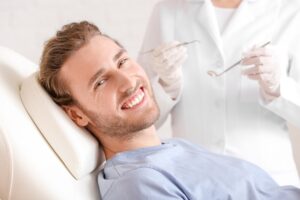 Man smiling in dentist's chair after getting dental implants