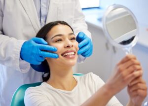 Woman looking in the mirror after getting a dental crown in Mount Pleasant, MI